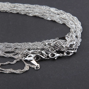 Detailed macro view of 18KGP silver water wave chains with secure lobster clasps