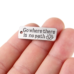 Dettaglio del ciondolo vintage in metallo inciso con Go where there is no path
