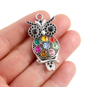 Silver owl pendant necklace featuring colorful rhinestones held in a hand for scale