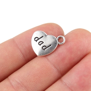 Macro detail of heart-shaped alloy pendant featuring engraved dad text and ring loop