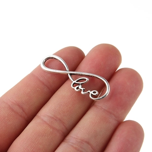 Detail shot of vintage silver infinity symbol and Love pendant charm for DIY jewelry making