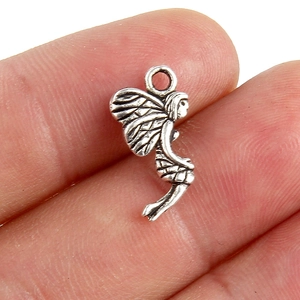Vue détaillée d'un pendentif fée argenté sur un doigt pour montrer sa petite taille