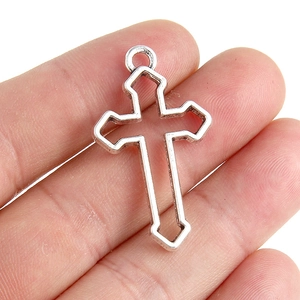 Pendentif croix évidée en argent antique tenu à la main montrant la taille et la texture