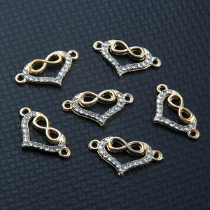 Vue détaillée de connecteurs de bijoux en cœur doré avec symboles infini et strass incrustés