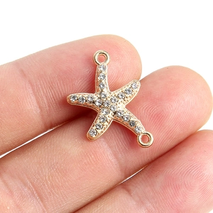 Détail d'un connecteur de bijoux étoile de mer doré avec strass et boucles doubles