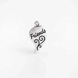 Gros plan d'un pendentif cœur en argent avec gravure Friends et motifs floraux