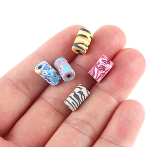 Gros plan de perles colorées en argile faites à la main avec motifs animaux et fleurs sur main
