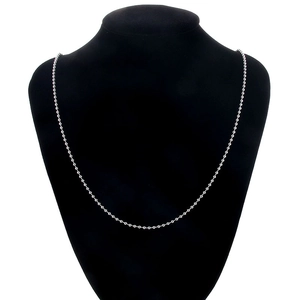 Gros plan d'un collier à billes en argent poli sur un support en velours noir