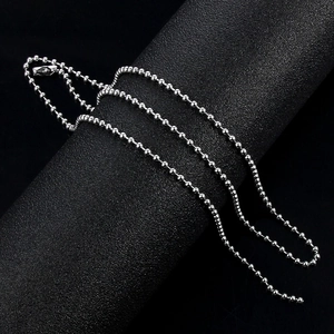 Collier chaîne à billes en acier inoxydable poli argent sur un support texturé sombre