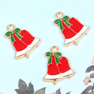 Detail van rode kerstbel hangers met groene strikken voor het maken van DIY sieraden en kettingen