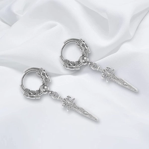 Detailed view of silver dragon sword earrings with gothic dagger pendants on white silk fabric