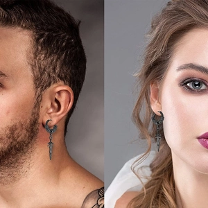Close-up of black gothic dagger earrings showing sword detail on both male and female models