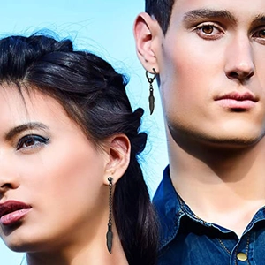 Detail of matte black feather dangle earrings worn by male and female models