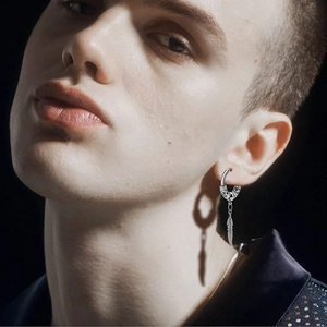 Detail of silver feather drop earring with vintage metal texture worn by male model