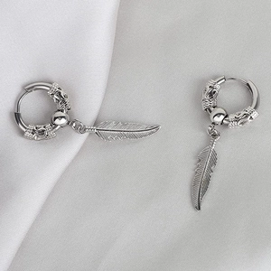 Detailed close-up of a silver hoop earring featuring a vintage feather pendant on silk