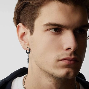 Close-up of a black feather pendant hoop earring worn by a male model in punk style