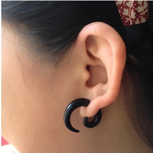 Close-up of black acrylic spiral snail ear gauge expander worn on a person's ear lobe