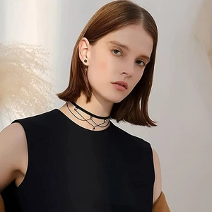 Gros plan sur un choker noir multicouche avec de petites boucles d'oreilles boules