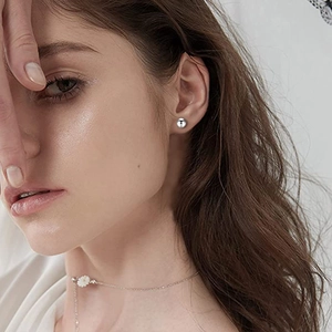 Gros plan de boucles d'oreilles boules en argent poli sur mannequin avec collier marguerite