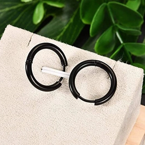 Set of minimalist black stainless steel hoop earrings on a textured jewelry display stand
