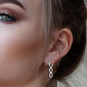 Minimalist silver infinity charm hoop earring worn by a model in a close-up side view