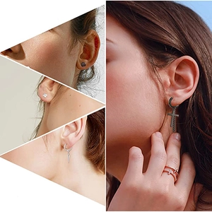 Detailed view of black cross dangle earrings and assorted stud earrings on model ear