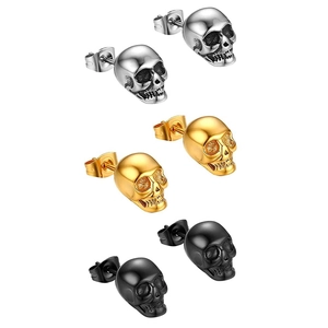 Macro detail of gothic skull stud earrings in silver, gold, and matte black steel