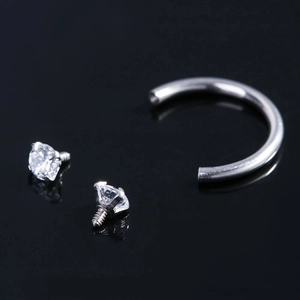 Macro detail of horseshoe barbell ring with screw-in cubic zirconia and silver steel finish