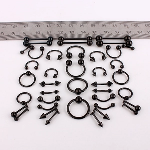 Set aus schwarzem Piercing-Schmuck aus Edelstahl mit Hanteln und Ringen sowie Lineal