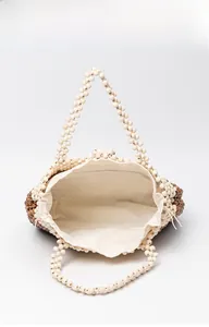 Detailed top view of a woven beaded tote bag with a canvas drawstring liner