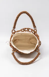 Detailansicht einer handgefertigten Holzperlen-Handtasche mit weißem Kordelzugbeutel.