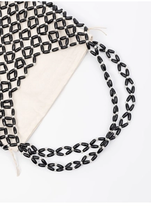 Detail showing hand-woven black and white beaded bag with beige drawstring inner pouch