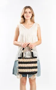 Detail of hand-woven beaded handbag with black and white floral patterns on a model
