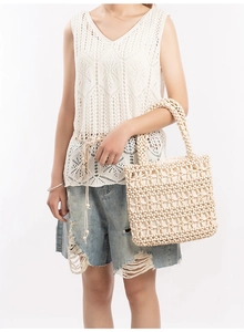 Detail of the woven bead handbag showing intricate cream white diamond patterns and handles
