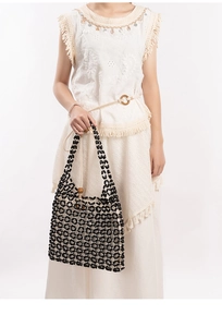 Detail of black beaded hollow tote bag with natural wood beads on a boho dress
