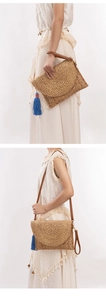 Detail of woven jute bag with blue tassels and leather strap showing versatile carrying options