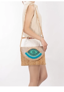 Detail of bohemian jute bag with blue evil eye beadwork and vibrant tassel fringe