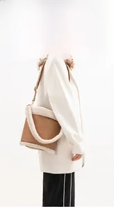 Macro detail of brown leather dumpling bag with white shearling trim and adjustable strap