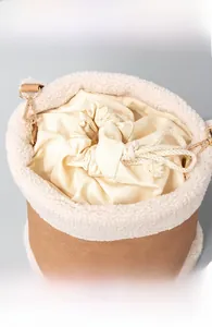 Detail of faux shearling trim and secure drawstring closure on retro bucket bag
