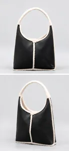 Macro view of black leather dumpling bag featuring contrast faux shearling fur trim detailing