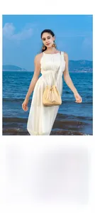 Detail of straw bucket bag featuring fringe drawstring and embroidered strap at beach
