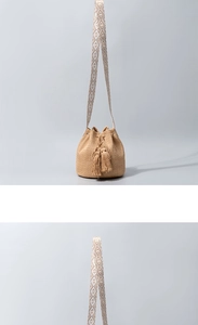 Detail of straw bucket bag with tassels and geometric ethnic style woven shoulder strap