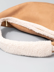 Brown leather dumpling bag with white faux fur trim and gold zipper for winter fashion