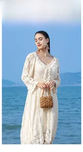 Brown handmade wood bead bag held by a model on a sunny beach background