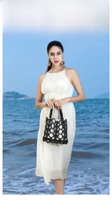 Outdoor shot of a black handmade beaded bag with white drawstring liner and wood handle
