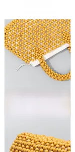 Detailed close-up of handmade yellow wood bead weave and natural texture on the handbag