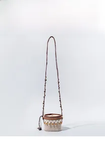 Close-up detail of ethnic woven pattern on straw bucket bag with dark brown strap