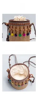Détail du sac seau en paille avec glands en perles de bois et broderie colorée