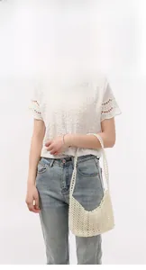 Détail du sac à bandoulière en perles crème au design épuré et forme en demi-lune