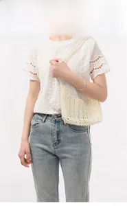 Vue détaillée du sac à main en perles blanches tressé avec un haut en dentelle blanche